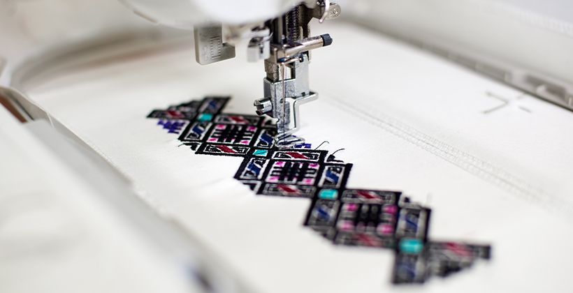 maquina de coser creando coloridos patrones geometricos abstractos sobre tela blanca